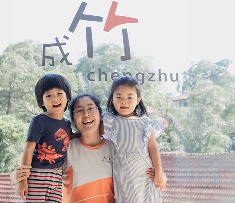 A-teacher-and-two-children-smile-together-for-a-photo-in-front-of-a-large-window-capturing-a-moment-of-joy---Chengzhu-Mandarin-Centre-crop