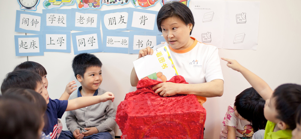 A-teacher-holds-a-book-while-guiding-students-in-a-Mandarin-group-learning-session---Chengzhu-Mandarin-Centre